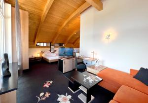 ein Wohnzimmer mit einem orangenen Sofa und ein Zimmer mit einem Bett in der Unterkunft Hotel Am Hirschhorn - Wellness - Spa - and more in Wilgartswiesen