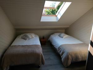 2 łóżka w pokoju na poddaszu z oknem w obiekcie Le manège Gite L'Eglise w mieście Sainte-Marie-au-Bosc