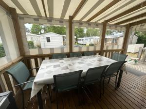 a porch with a table and chairs on a deck at Les sables chal’heureux in Saint-Jean-de-Monts