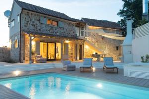 a swimming pool with chairs and a house at Dolce Terra in Stari Grad