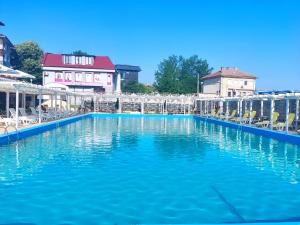 una gran piscina de agua azul con sillas y edificios en Hotel Elit, en Kirkovo