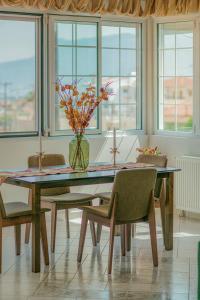 einen Esstisch mit Stühlen und eine Vase mit Blumen in der Unterkunft AKANTHOS Rental House in Kórinthos