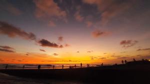 a group of people standing on the beach at sunset at Spaces Bali Unique Boutique Hotel in Munggu