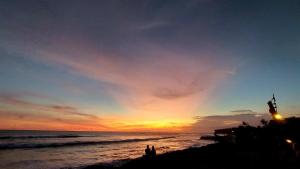 a sunset at the beach with people standing on the beach at Spaces Bali Unique Boutique Hotel in Munggu