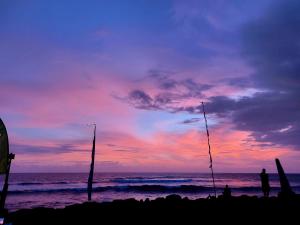 a person standing on a beach with a sunset at Spaces Bali Unique Boutique Hotel in Munggu