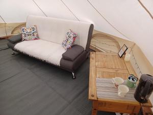 a couch in a tent with a coffee table at Tryfan Pen Cefn Farm Bell Tent in Abergele