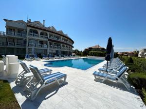 a swimming pool with lounge chairs and a hotel at Apolonia Apartments in Sozopol
