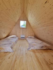 two beds in a wooden room with a window at GLAMPING HOUSE ˇVITAˇ in Tolmin