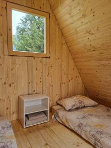 una camera con due letti e una finestra in una baita di tronchi di GLAMPING HOUSE ˇVITAˇ a Tolmin