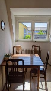 een houten tafel en stoelen in een kamer met 2 ramen bij Klostereck (Villa C. Haas) in Sankt Georgen im Schwarzwald