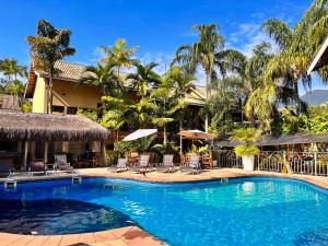 una piscina frente a una casa con palmeras en Suite 1110 IlhaFlat, en Ilhabela