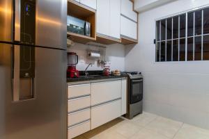 a kitchen with white cabinets and a stainless steel refrigerator at Nosso apto em Pinhal in Espirito Santo Do Pinhal +3 photos