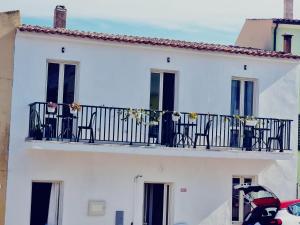 a white building with a balcony with chairs on it at Suite Cornelia in Santa Teresa Gallura
