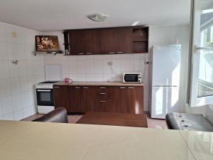 a kitchen with wooden cabinets and a white refrigerator at Casa Cris Will in Mamaia Nord
