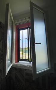 ein Fenster in einem Zimmer mit Blick auf ein Feld in der Unterkunft Sala dell Estate Guest House in Secchia