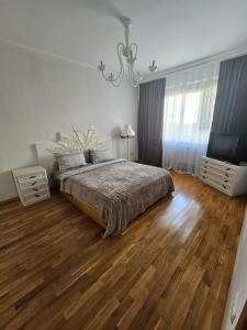 1 dormitorio con cama, suelo de madera y lámpara de araña en Negruzzi 2 bedrooms, en Chişinău