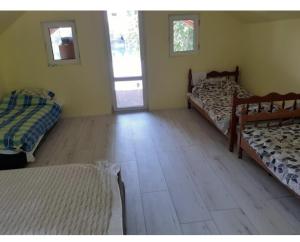 a bedroom with two beds and a wooden floor at green house at silver lake in Ostrovo