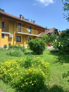 a yellow house with yellow flowers in the yard at Sobe Dujakovic 
