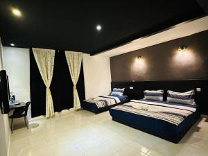 een slaapkamer met 2 bedden en een zwarte muur bij Kuu Inn Motel in Arau
