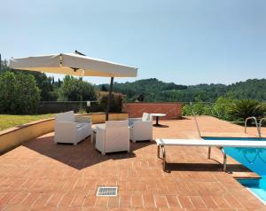 a patio with chairs and an umbrella next to a pool at Gervasella in Pontedera