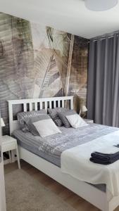 sypialnia z białym łóżkiem i malowidłem ściennym w obiekcie apartament przy plaży w redłowie w mieście Gdynia
