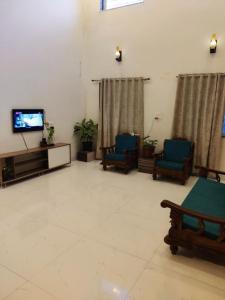 a living room with two chairs and a tv at Myra's house in Kolhapur