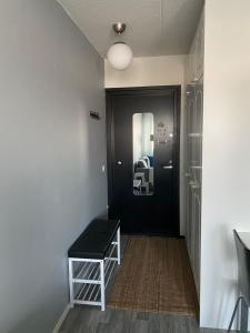 un pasillo con una puerta negra y un taburete en Viihtyisä huoneisto keskustassa., en Kotka