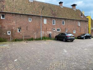 dos coches estacionados frente a un gran edificio de ladrillo en Hotelkamer Prinsenstraat with Free Parking en Groningen