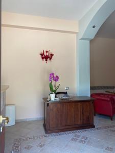 una habitación con una mesa con un jarrón con flores púrpuras. en Villa Vittoria, en Matera