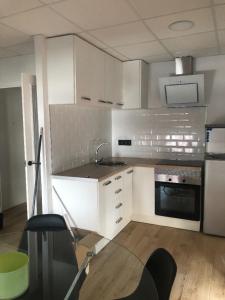 uma cozinha com armários brancos, um lavatório e um fogão em LA PEPITA em Sant Carles de la Ràpita