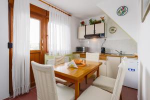 - une cuisine avec une table en bois et des chaises blanches dans l'établissement Apartment Žalac, à Slunj
