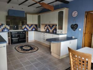 uma cozinha com armários brancos e uma parede azul em 3 bedroom farmhouse in Normandy em Gathemo