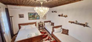 a bedroom with two beds and a chandelier at Guesthouse Alvaro Kadiu in Berat