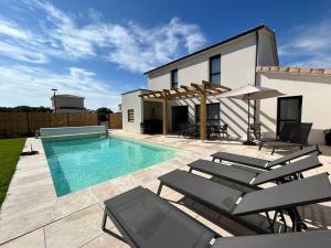 a villa with a swimming pool and some chairs at La Forêt d'Armotte villa 14 in Saint-Augustin