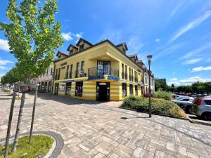 a yellow building on a street with a parking lot at Penzion Félix in Topoľčany