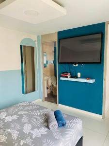 1 dormitorio con pared azul y TV de pantalla plana en Amplio e iluminado Apartamento, en Yopal