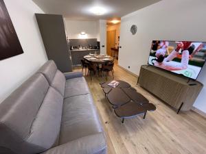 a living room with a couch and a tv and a table at GESPERE LE STELLA in Les Gets