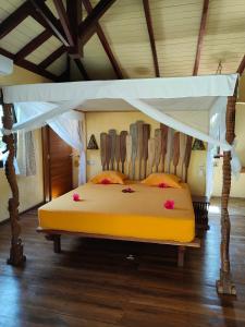- une chambre avec un lit jaune à baldaquin dans l'établissement Villa Mbolatsara, à Nosy Be