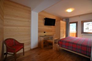 a bedroom with a bed and a table and a tv at Hotel La Montanina in Alleghe