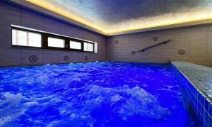a large swimming pool with blue water in a room at Grand Lake House in Giurcuţa de Sus