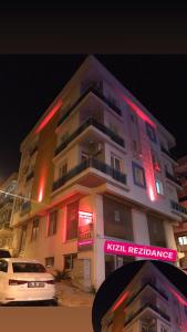 um edifício alto com sinais de néon à frente em kızıl apart em Buca