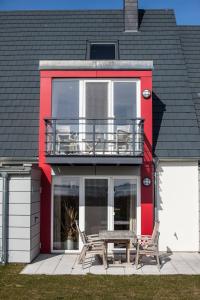 une maison rouge avec un banc et un balcon dans l'établissement Ferienwohnung Aalfänger, à Breege