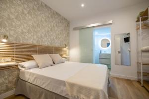 1 Schlafzimmer mit einem großen weißen Bett und einem Badezimmer in der Unterkunft Hostal Royal Bliss in Punta Umbría