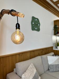 a light hanging over a couch with a clock on the wall at Pirin Golf & Spa Greenside Studio in Razlog
