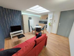 ein Wohnzimmer mit einem roten Sofa und einem Tisch in der Unterkunft ° Appart 4 - Lunéville centre ° in Lunéville