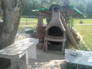 a outdoor oven with a bench next to a tree at Hiška Zeleni raj in Podnart