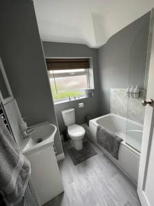 a bathroom with a toilet and a tub and a sink at Fabulous 3bed off street parking in Stafford
