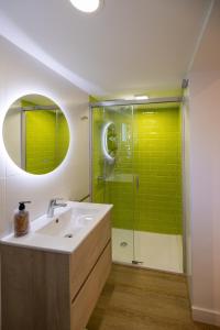 baño con lavabo y ducha con azulejos verdes en Hostal Royal Bliss en Punta Umbría