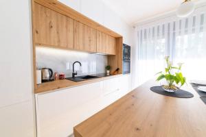 a kitchen with white cabinets and a wooden table at Apartman Lux in Virovitica