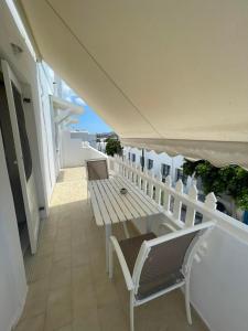 Un balcón con sillas blancas y un banco de madera. en Yannis Maria Rooms, en Antíparos